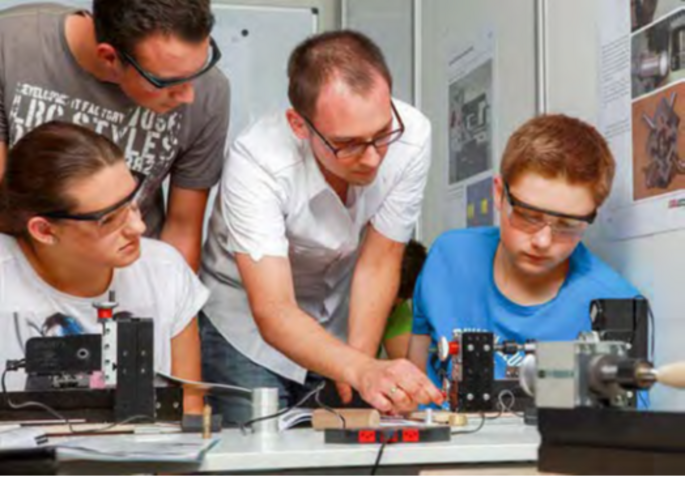 Schüler und Lehrer arbeiten gemeinsam mit der UNIMAT MetalLine Drehbank, Lehrer erklärt die Funktionsweise der Drehbank