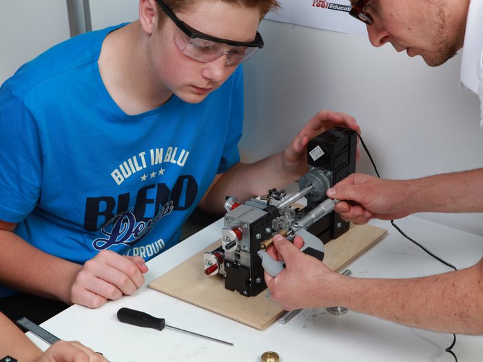 UNIMAT Technikset im Unterricht, Lehrer misst mit Schüler gemeinsam ein Werkstück